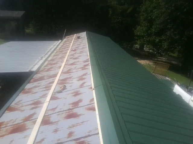 Old rusted panels beside newly installed green metal roofing — Wind Damage Roof Repair by Roofing Brothers in Green Village
