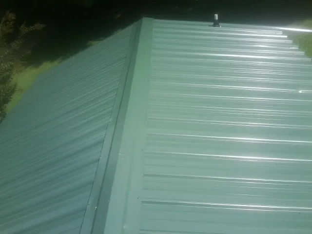 New green metal panels meeting at the ridge of a roof — Flat Roof Repair work by our crew in Green Village