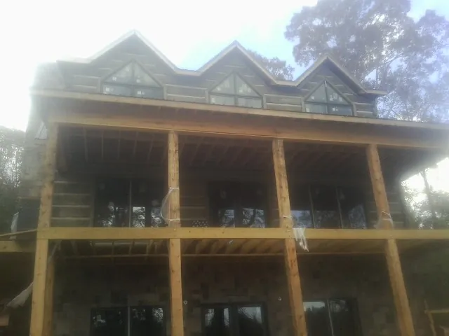 Dormers and porch framing on a large log home under construction — Roof Coating work by our crew in Green Village