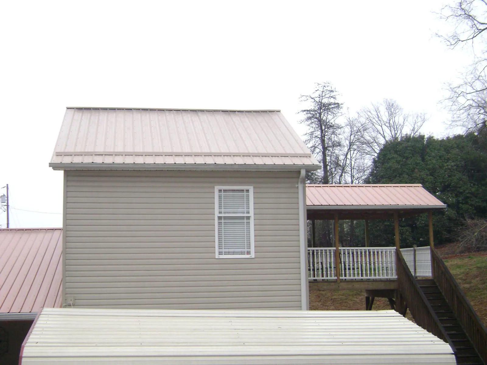 Tan metal roofs on a two story addition and attached porch, from a Roof Replacement job in Green Village