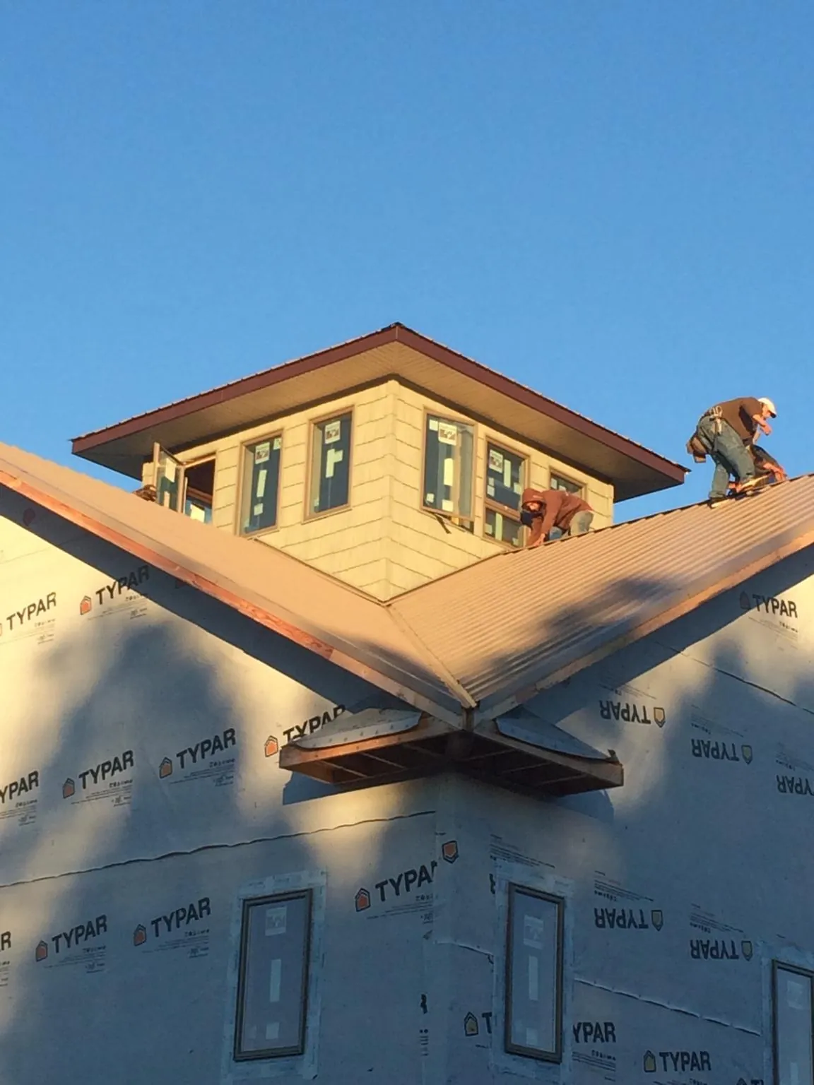 Roofers working around a rooftop cupola on a new metal roof at sunset — Roof Waterproofing in Green Village by Roofing Brothers